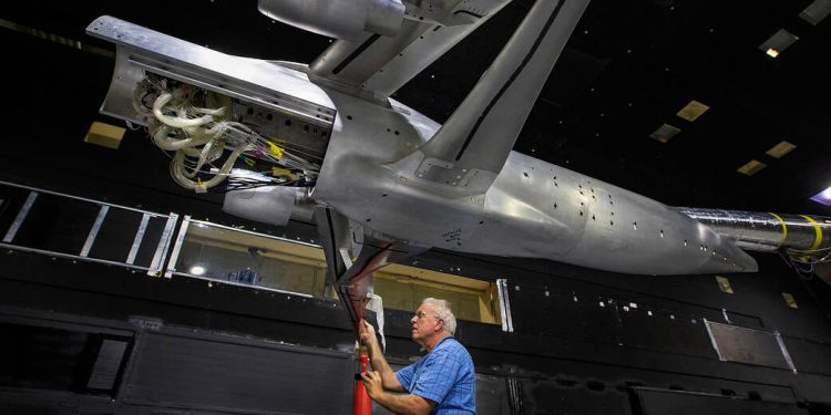 El técnico de instrumentación Michael Hodgins lleva a cabo las medidas de instalación en el modelo de ala reforzada con armadura trans-sónica (TTBW) en el túnel de viento subsónico de 14x22 del Langley Research Center.