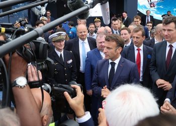 Macron escucha al CEO de Dassault Aviation, Eric Trappier, junto a una réplica de un avión de combate Rafale, durante su visita al Salón.