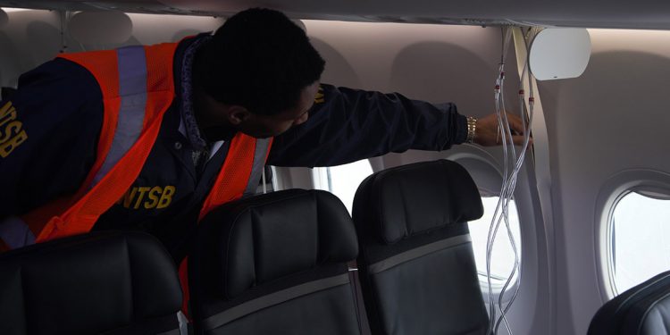 El investigador de la NTSB, Dujuan Sevillano, examina los paneles laterales interiores del vuelo 1282 de Alaska Airlines, un Boeing 737-9 MAX.